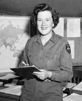 Julia Child in OSS military uniform smiling while holding clipboard during World War II